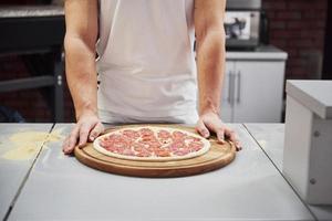 isso vai ser delicioso. close-up vista do padeiro com pizza que está pronta para colocar no forno para cozinhar foto