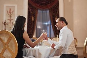 senta-se contra a janela. lindo casal jantar romântico no restaurante de luxo à noite foto