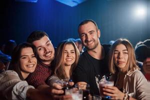 beber a noite toda. grupo de jovens amigos sorrindo e fazendo um brinde no clube foto