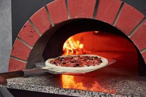 colocando pizza dentro. fogo queimando na fornalha. close-up vista de madeira em chamas foto