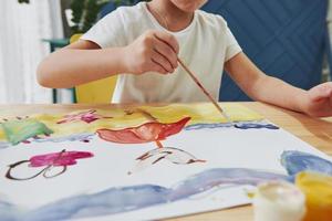 vista de perto. menina está desenhando usando guache e pincel. aprendendo na aula de arte foto