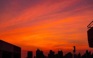 edifício da cidade à noite com lindo céu vermelho por do sol e nuvens. paisagem urbana com céu pôr do sol vermelho e laranja. crepúsculo com paisagem urbana. citação de fundo para a vida depois do trabalho o dia todo. foto