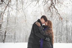 menina sorrindo. lindo casal jovem se diverte juntos na floresta nevada foto