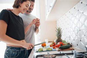 provar essa maçã. jovem casal na cozinha moderna em casa no fim de semana pela manhã foto