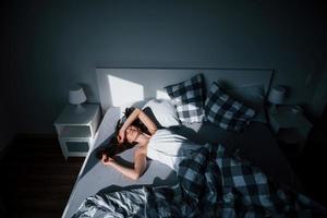 lugar confortável. bela jovem deitada na cama na hora da manhã em seu quarto foto