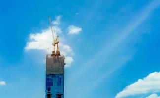 canteiro de obras com guindaste e construção. setor imobiliário. guindaste usar carretel levantar equipamentos no canteiro de obras. edifício feito de aço e concreto. trabalho de guindaste contra o céu azul com luz solar. foto