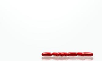 comprimidos de cápsula vermelha isolados no fundo branco com sombras e espaço de cópia para texto. vitamina e suplemento para gravidez e idosos. foto