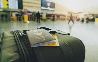 passaporte tailândia e passaporte vacinal na bagagem em desfocar o fundo do turista no aeroporto. certificado de vacinação para viagens durante o surto de coronavírus. palavras tailandesas são passaporte de tailândia. foto