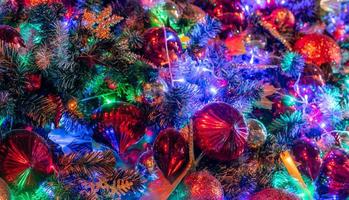 feche a decoração da árvore de natal com bola vermelha e luzes. fundo de natal. fundo de férias de natal e feliz ano novo. lindas bolas coloridas na árvore de natal. foto