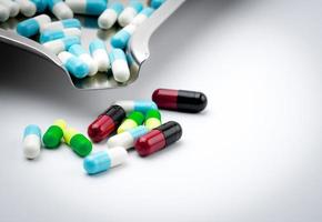 pílulas de cápsulas coloridas na bandeja de drogas de aço inoxidável em fundo branco. closeup muitos da cápsula com tamanho diferente na mesa branca. foto