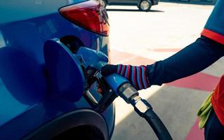 carro abastecendo no posto de gasolina. reabastecer abastecer com gasolina gasolina. bomba de gasolina enchendo o bocal de combustível no tanque de combustível do carro no posto de gasolina. indústria e serviços petrolíferos. preço da gasolina e conceito de crise do petróleo. foto