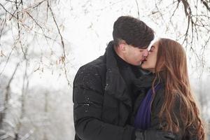 beijos lindos. lindo casal jovem se diverte juntos na floresta nevada foto