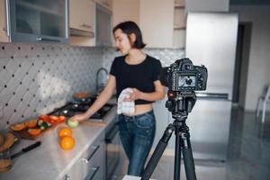 equipamento de estúdio profissional caro. garota na cozinha moderna em casa em seu horário de fim de semana pela manhã foto