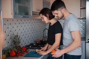 marido indo atrás. jovem casal na cozinha moderna em casa no fim de semana pela manhã foto