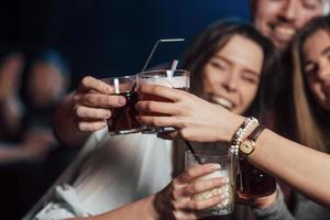 processo tradicional de copos. grupo de jovens amigos sorrindo e fazendo um brinde na boate foto