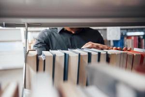 Visão detalhada. homem afro-americano na biblioteca procurando algumas informações nos livros foto