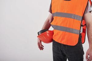 visão de partículas. homem de uniforme laranja fica contra um fundo branco no estúdio foto