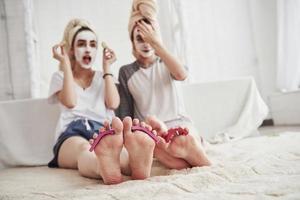 foto focada nos pés. pedicure e unhas pintadas nas pernas. concepção de cuidados com a pele usando máscara branca e pepinos no rosto