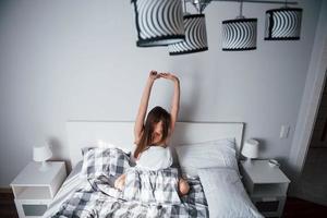 lâmpadas interessantes. bela jovem deitada na cama na hora da manhã em seu quarto foto