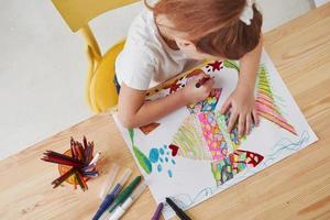 ela adora essa ocupação. menina bonitinha na escola de arte desenha suas primeiras pinturas com lápis e marcadores foto
