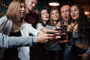 caras engraçadas. grupo de jovens amigos sorrindo e fazendo um brinde na boate foto