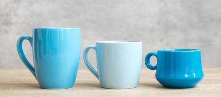 xícara de café azul e caneca de chá no fundo da mesa de madeira pela manhã, espaço de cópia em branco para texto. dia internacional do café e conceito de rotina diária foto