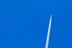 avião com faixas de condensação brancas. avião a jato no céu azul e nuvens brancas com trilha de vapor. viajar pelo conceito de avião. trilhas de gases de escape do motor do avião. aeronaves com listras brancas. foto