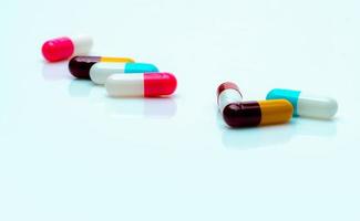 pílulas de cápsulas antibióticas multicoloridas espalhadas no fundo branco. resistência a antibióticos. pílulas cápsula antimicrobiana. indústria farmacêutica. comprimidos cápsula rosa, branco, azul, amarelo e vermelho. foto
