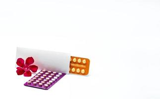 pílulas anticoncepcionais ou pílulas anticoncepcionais com flor rosa em fundo branco. hormônio para contracepção. comprimidos hormonais redondos brancos em blister. farmácia drogaria. conceito de seleção de drogas. foto