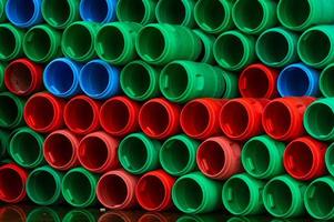 barris de plástico usados. tambor de plástico azul, verde e vermelho. empilhado de tanque vazio na fábrica de alimentos à espera de reciclagem e reutilização. recipiente de matéria-prima na indústria de fabricação de alimentos. tambor de plástico velho foto