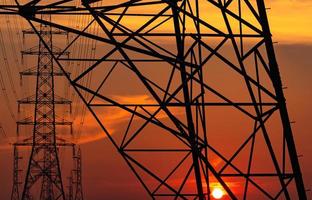 poste elétrico de alta tensão e linhas de transmissão à noite. postes de eletricidade ao pôr do sol. potência e energia. conservação de energia. torre de grade de alta tensão com cabo de arame na estação de distribuição. foto