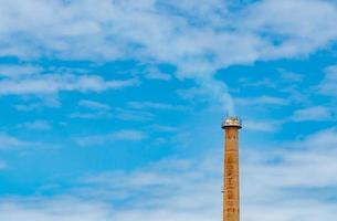 cachimbo de fumaça enferrujado da fábrica contra o céu azul e nuvens brancas. fumaça branca da chaminé do tubo industrial. ar limpo ao redor da fábrica. gestão ambiental na fábrica de fabricação. foto