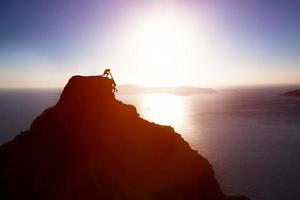 alpinista dando a mão e ajudando seu amigo a chegar ao topo da montanha. ajudar, apoiar foto