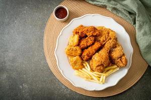 frango frito com batatas fritas e nuggets no prato foto