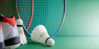 equipamentos de esporte de badminton em petecas de piso verde, raquetes, sapatos, foco seletivo em petecas, conceito de amante de jogo de esporte de badminton. foto