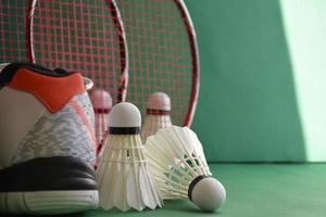 equipamentos de esporte de badminton em petecas de piso verde, raquetes, sapatos, foco seletivo em petecas, conceito de amante de jogo de esporte de badminton. foto