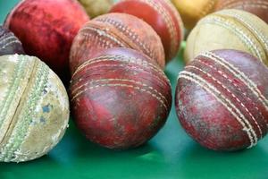 closeup bolas de críquete de couro velhas e usadas no chão verde, foco suave e seletivo. conceito para amante de críquete em todo o mundo. foto