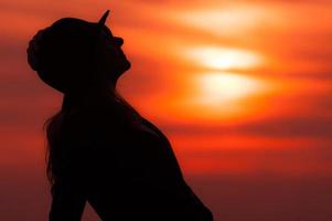 silhueta de mulher ao pôr do sol com céu vermelho foto