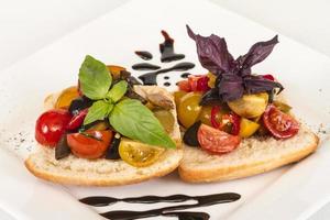 tomates suculentos no pão fresco, pesto como cobertura foto