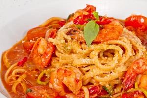 um prato de linguini com camarão salteado, tomate, pimentão e azeite foto