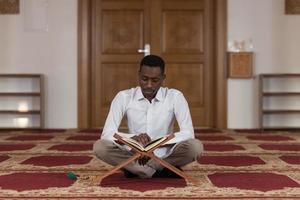 jovem muçulmano africano lendo o Alcorão foto