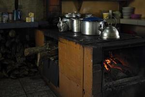 cozinha tradicional com fogão a lenha e panelas e frigideiras de metal. foto