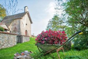 carrinho de mão cheio de flores em uma vila no norte da itália foto