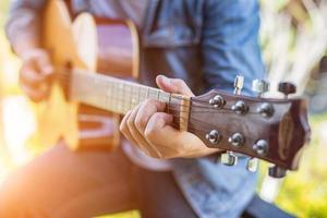 homem jovem hippie tocando guitarra para relaxar em suas férias, divirta-se com ar natural e fresco. foto