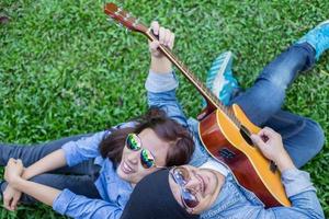 homem hipster tocando violão para sua namorada ao ar livre contra a parede de tijolos, curtindo juntos. foto