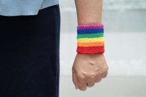 senhora asiática usando pulseiras de bandeira do arco-íris, símbolo do mês do orgulho LGBT, comemora anual em junho social de gays, lésbicas, bissexuais, transgêneros, direitos humanos. foto