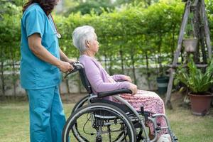médico cuidador ajuda e cuida paciente idosa asiática ou idosa sentada na cadeira de rodas no parque no hospital de enfermagem, conceito médico forte e saudável foto