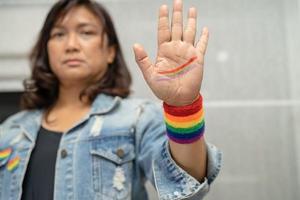 senhora asiática usando pulseiras de bandeira do arco-íris, símbolo do mês do orgulho LGBT, comemora anual em junho social de gays, lésbicas, bissexuais, transgêneros, direitos humanos. foto