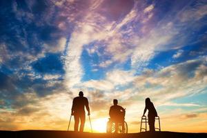 três pessoas com deficiência no pôr do sol. foto