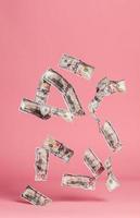 notas de dólar caindo no fundo rosa. foto